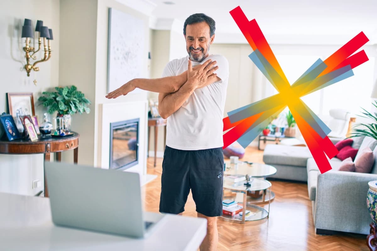 A man stretches his arm while smiling in a bright, cozy living room,.