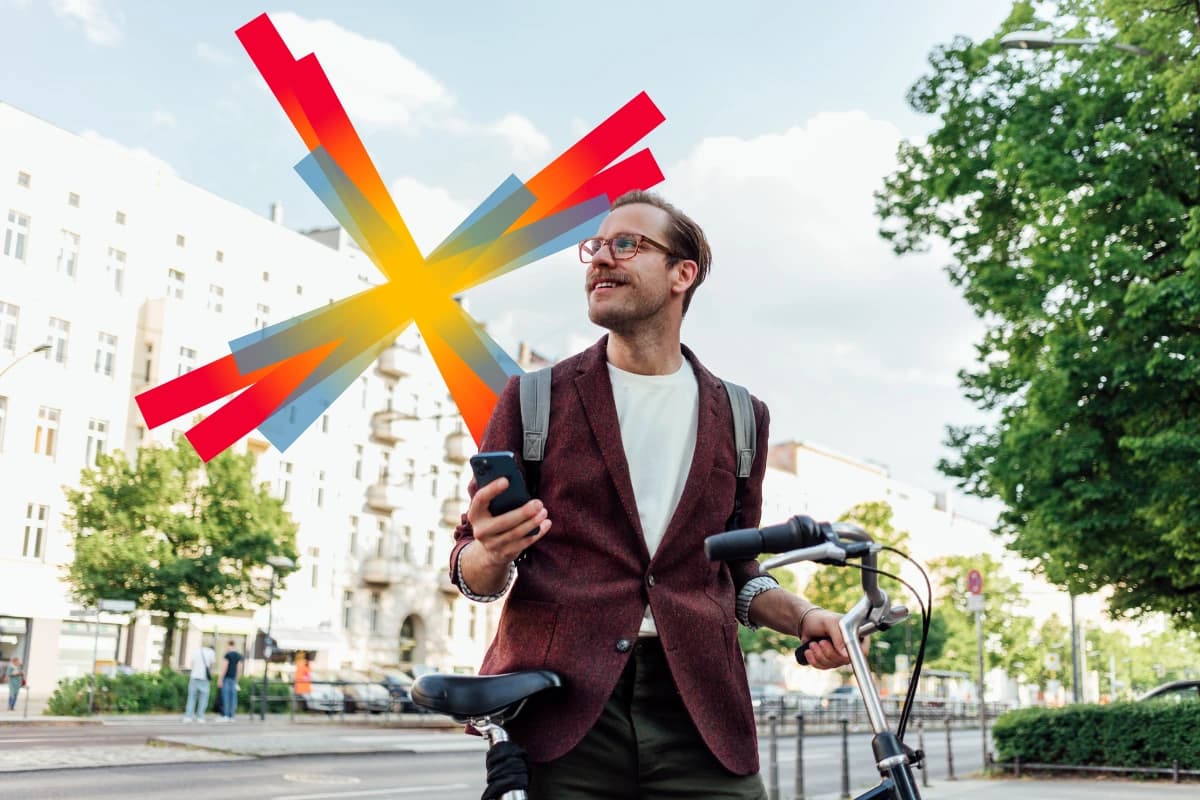 Man in brown jacket with bike and holding mobile phone 