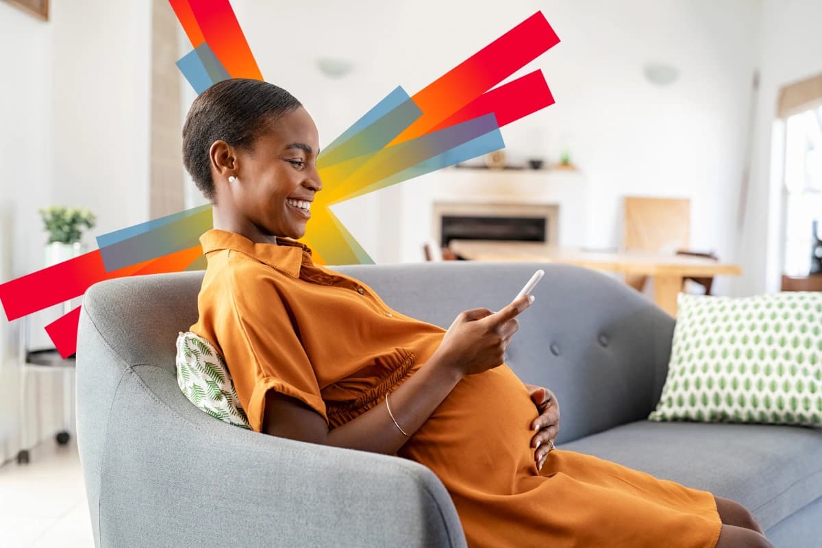 Pregnant woman sitting on sofa holding phone