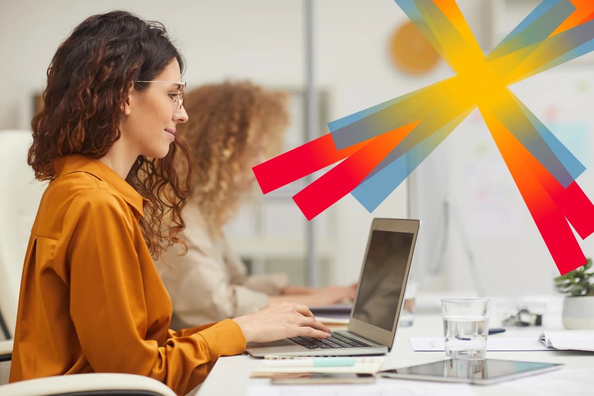 Woman in orange blouse sitting at laptop