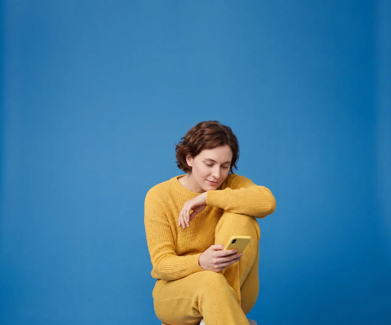 a woman in yellow looking at her phone