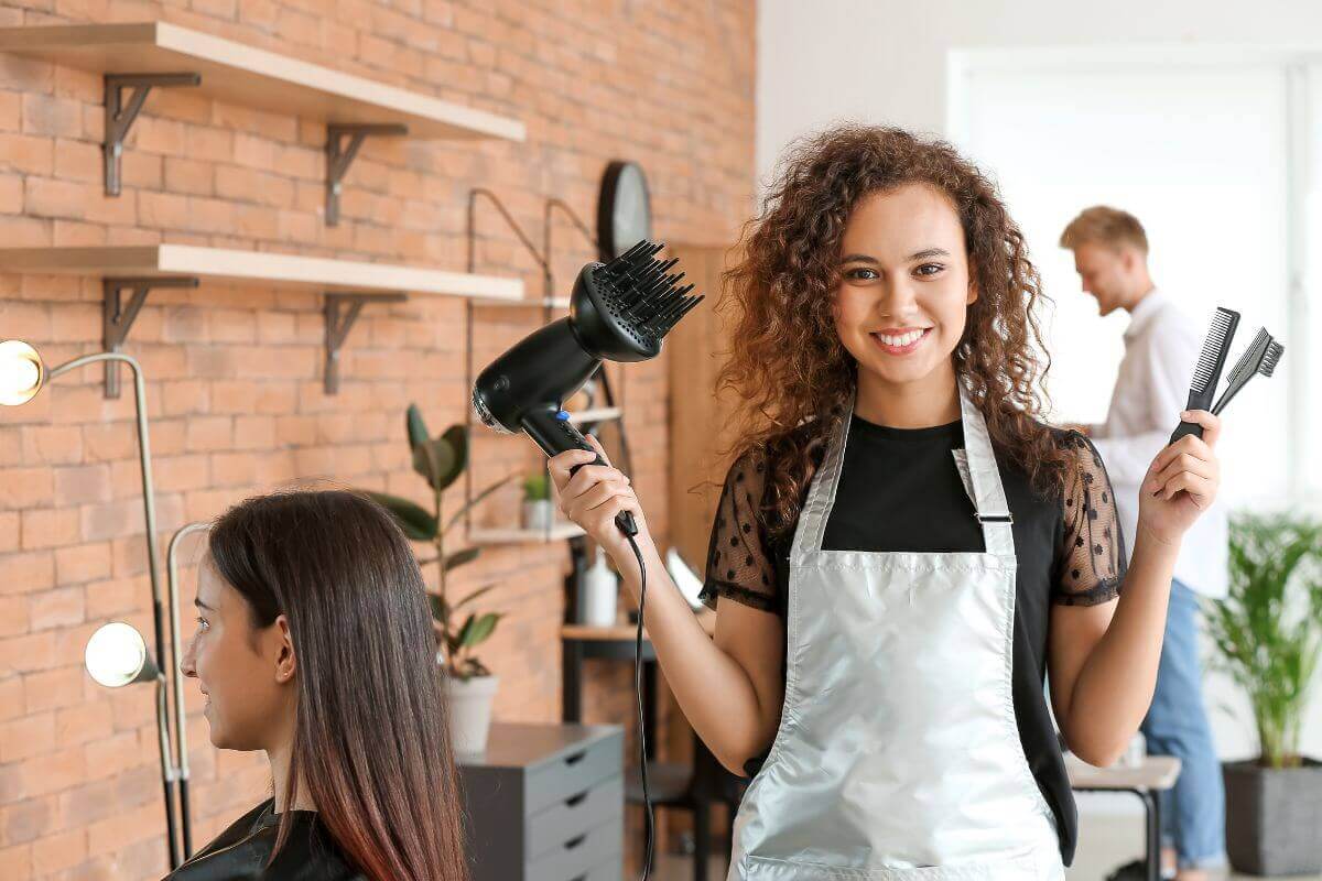Female hairdresser holding hairdryer and scissors 